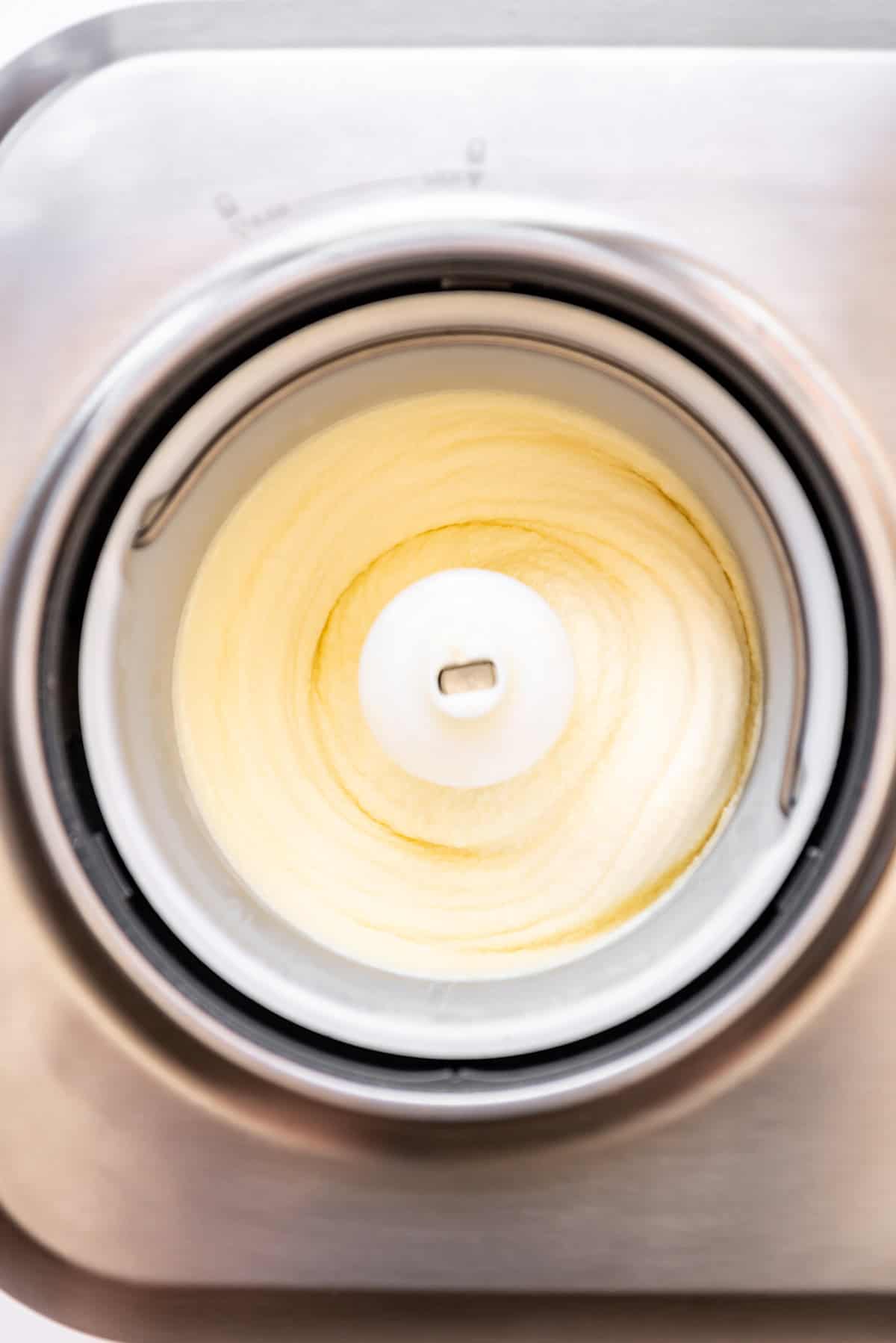 An overhead image of vanilla ice cream churning in a machine.