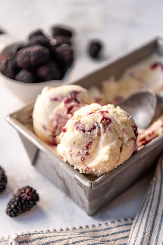 Two large scoops of homemade blackberry ice cream in the container it was frozen in.