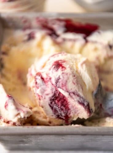 A close image of a swirls of blackberry puree in vanilla ice cream.