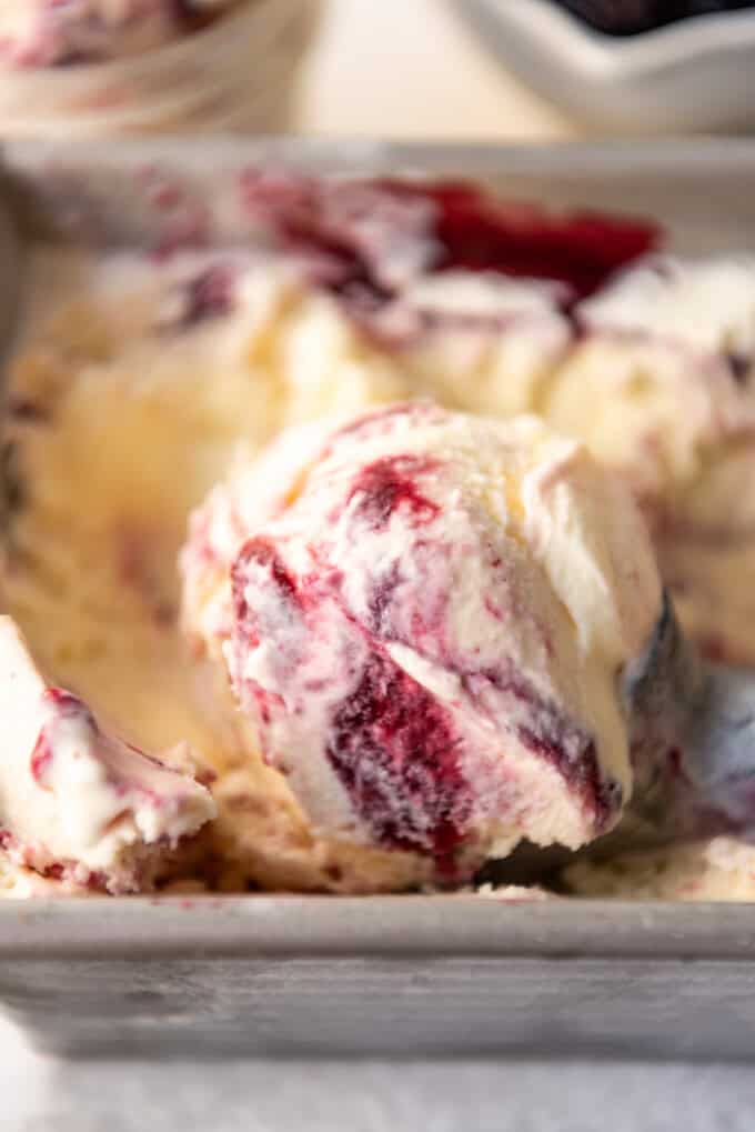 A close image of a swirls of blackberry puree in vanilla ice cream.