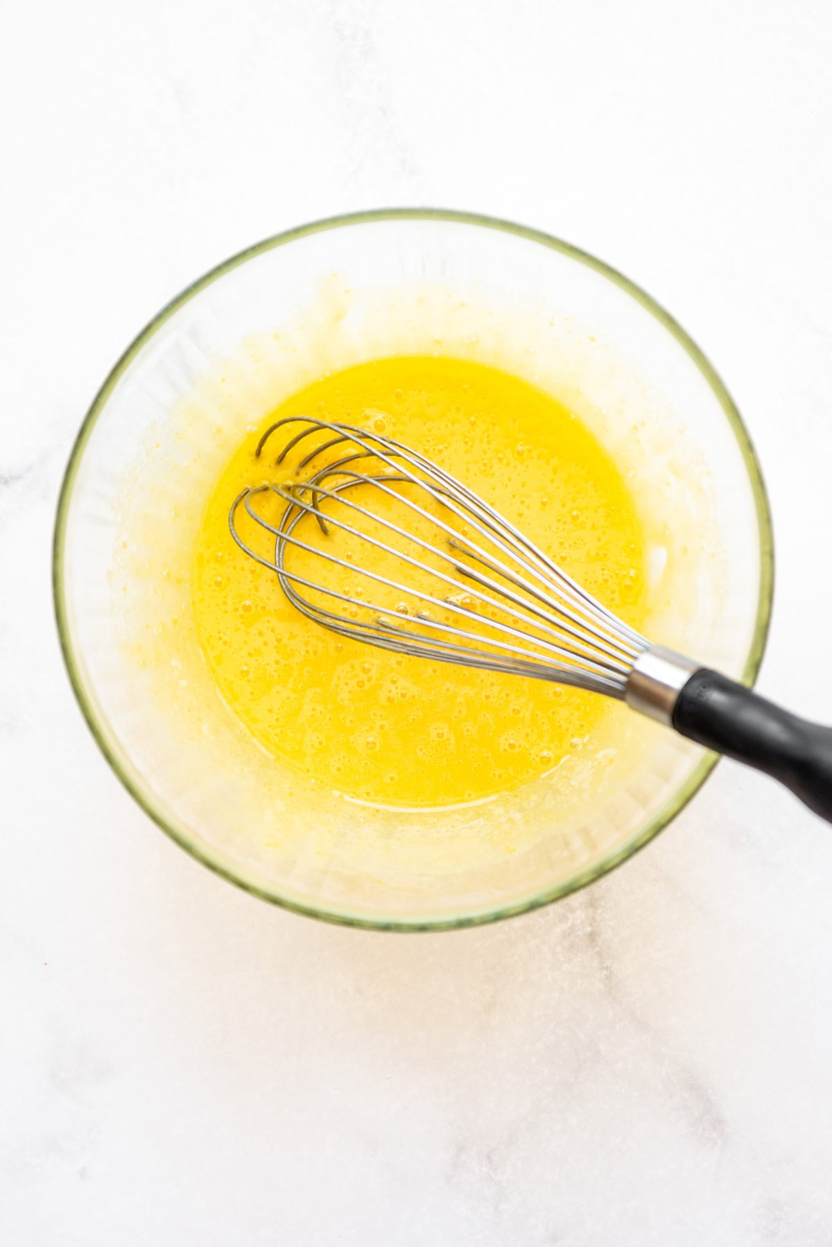 Whisked egg yolks and sugar in a bowl with a whisk.