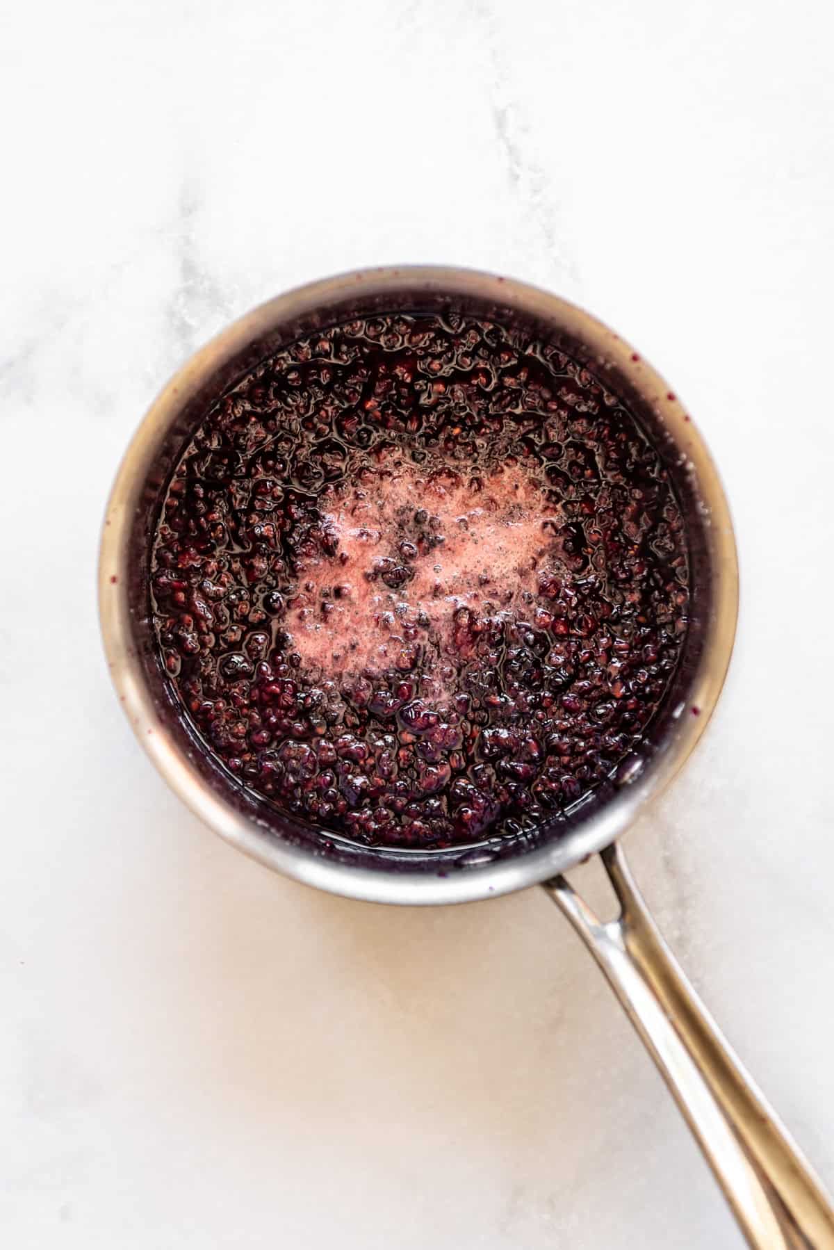 Boiling blackberry jam in a saucepan.