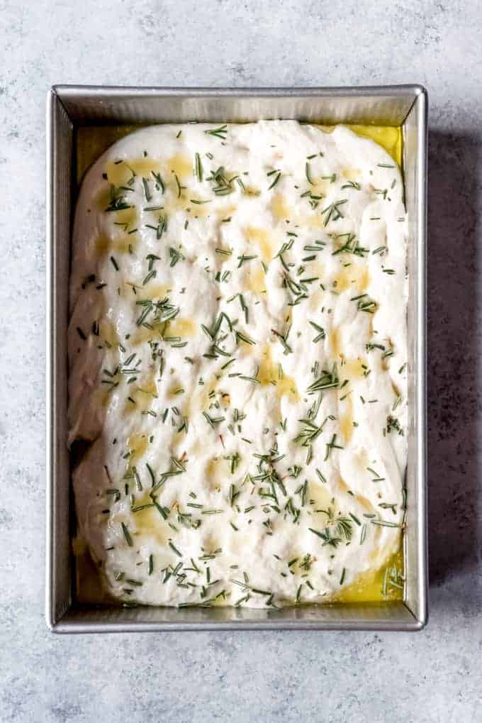 An image of a 9x13-inch pan filled with easy focaccia bread dough topped with olive oil, rosemary, and sea salt.