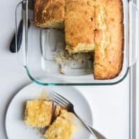 Homemade cornbread in a square baking dish with some slices removed.