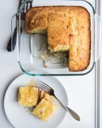 Homemade cornbread in a square baking dish with some slices removed.