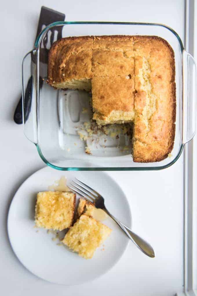 Homemade cornbread in a square baking dish with some slices removed.