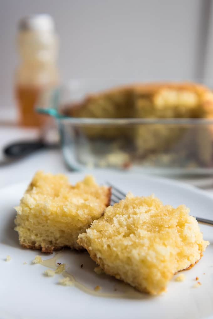 A slice of cornbread topped with honey on a plate.