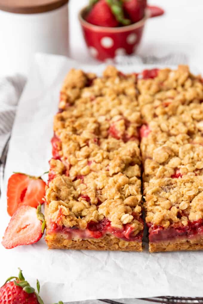 Strawberry rhubarb crumb bars from the side showing layers of jammy fruit filling between oatmeal cookie.
