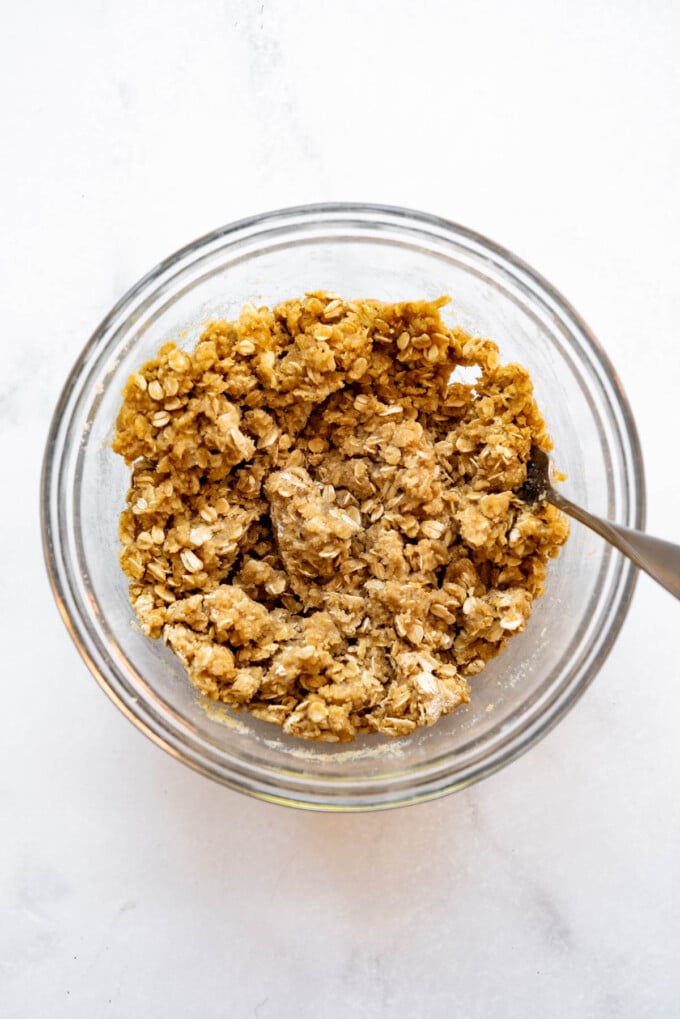 A moistened oat crumble mixture in a glass bowl.