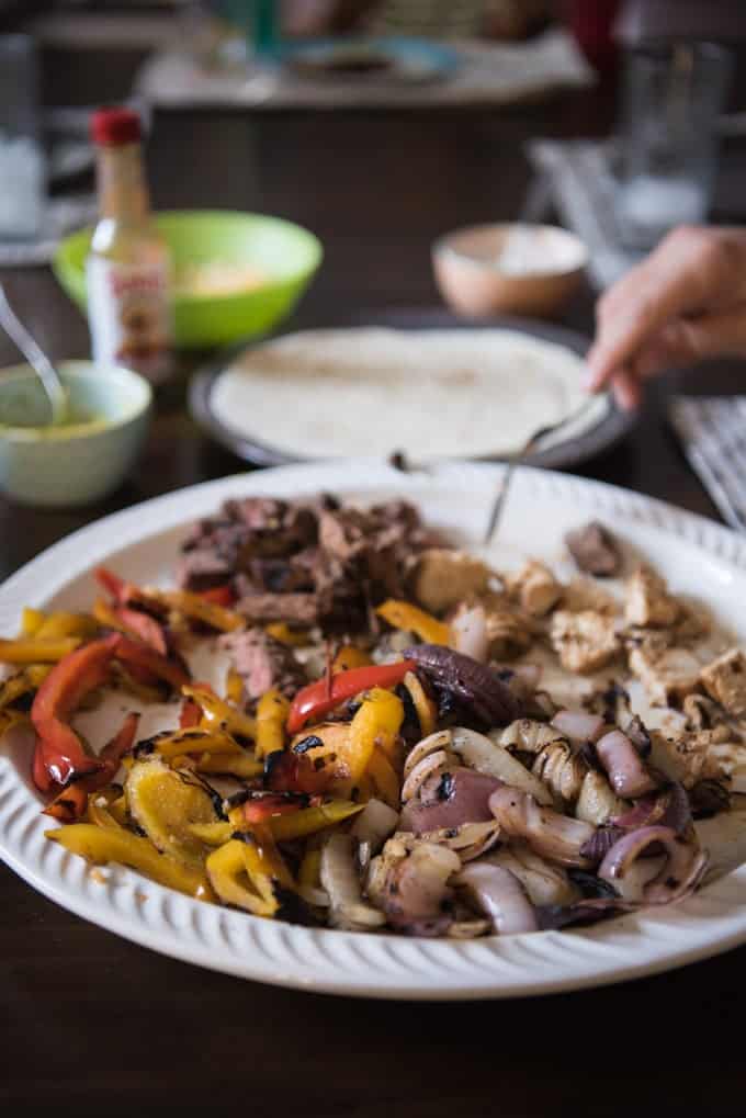 Grilled fajita vegetables with grilled chicken and steak on a large serving platter.