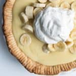 A banana cream pie topped with fresh banana slices and whipped cream.