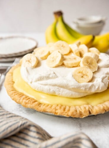 An old-fashioned banana cream pie topped with whipped cream and fresh sliced bananas.