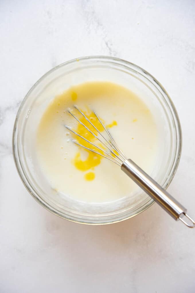 Adding tempered eggs into thickened milk and cream with cornstarch.