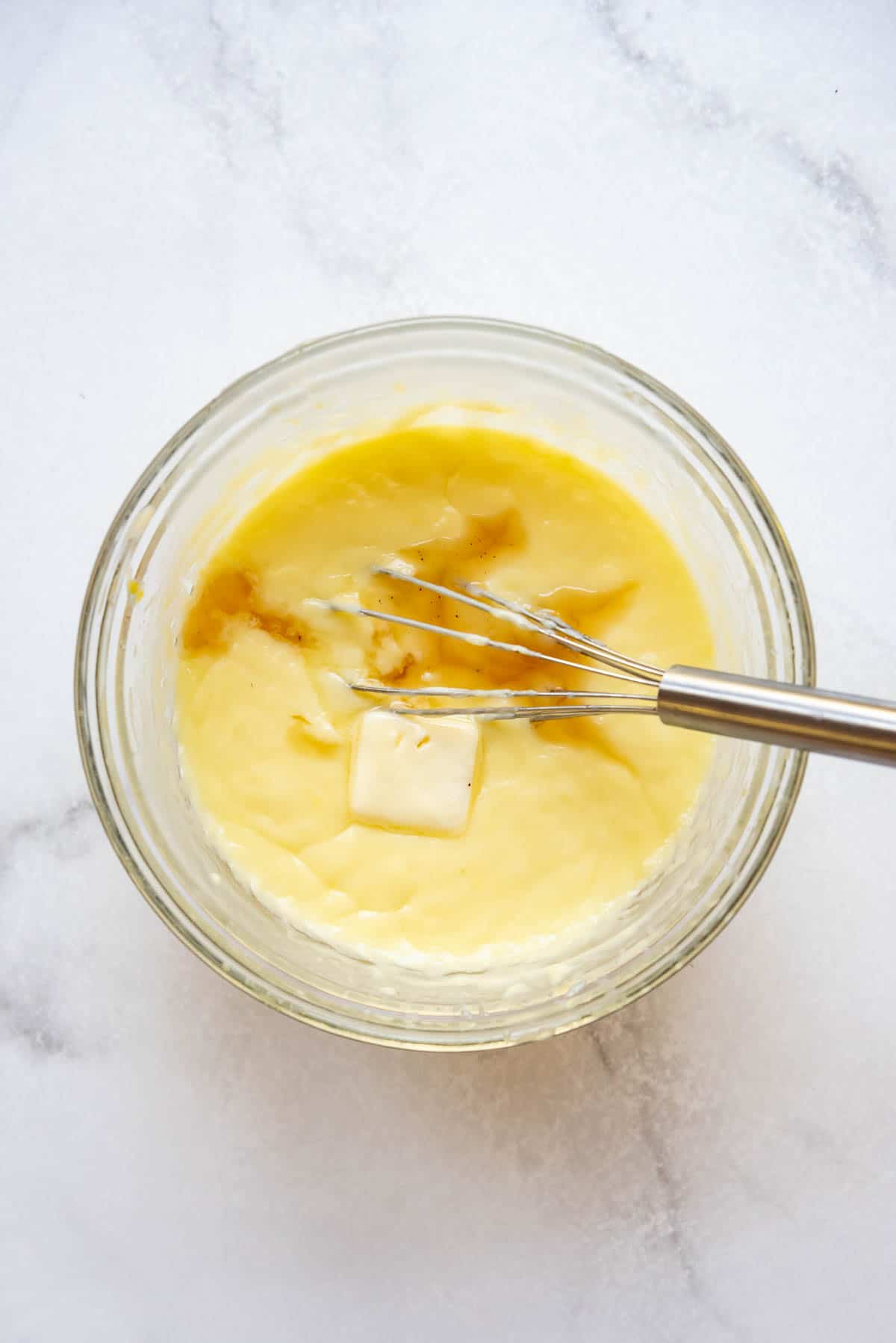 Whisking butter and vanilla into homemade custard pudding mixture for a banana cream pie.