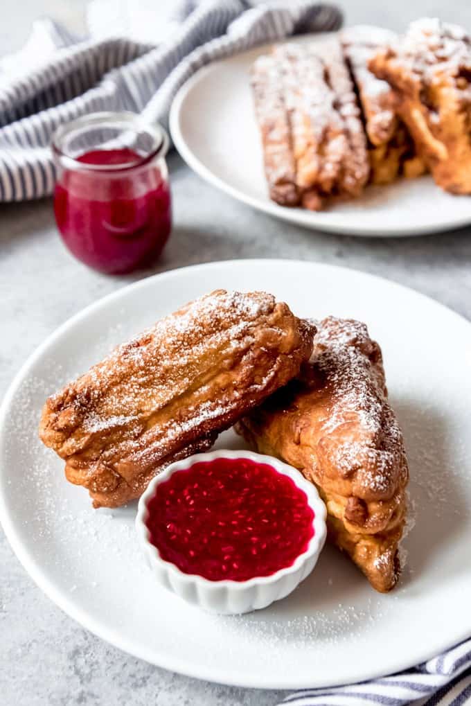 An image of a battered and fried Monte Cristo Sandwich that has been dusted with powdered sugar and served with raspberry jam for dipping.