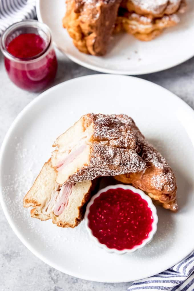 An image of a Monte Cristo ham and cheese sandwich on a white plate with jam for dipping.