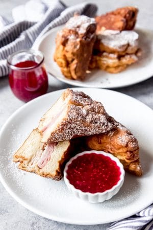 An image of a Monte Cristo ham and cheese sandwich on a white plate with jam for dipping.
