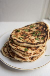 A plate of stacked garlic naan bread.