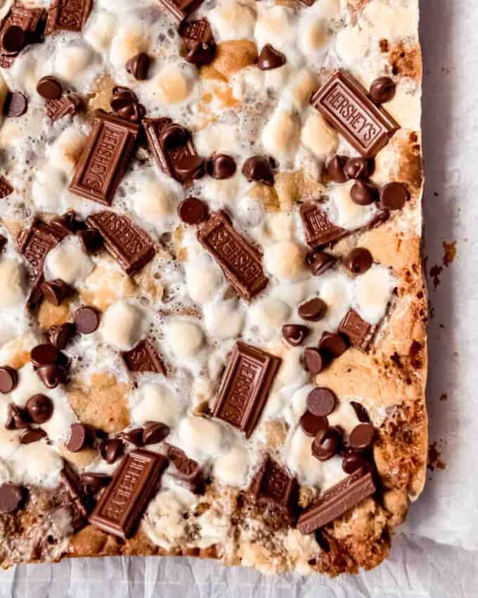 An image of s'mores cookie bars topped with toasted marshmallows and melted Hershey's chocolate.