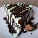 a straight view of a slice of Grasshopper Ice Cream Pie covered in chocolate sauce