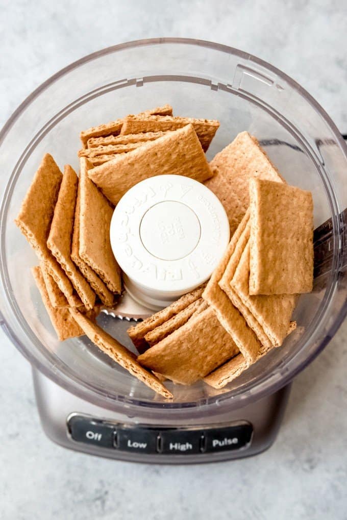 An image of graham crackers in a food processor to be pulsed into fine crumbs.