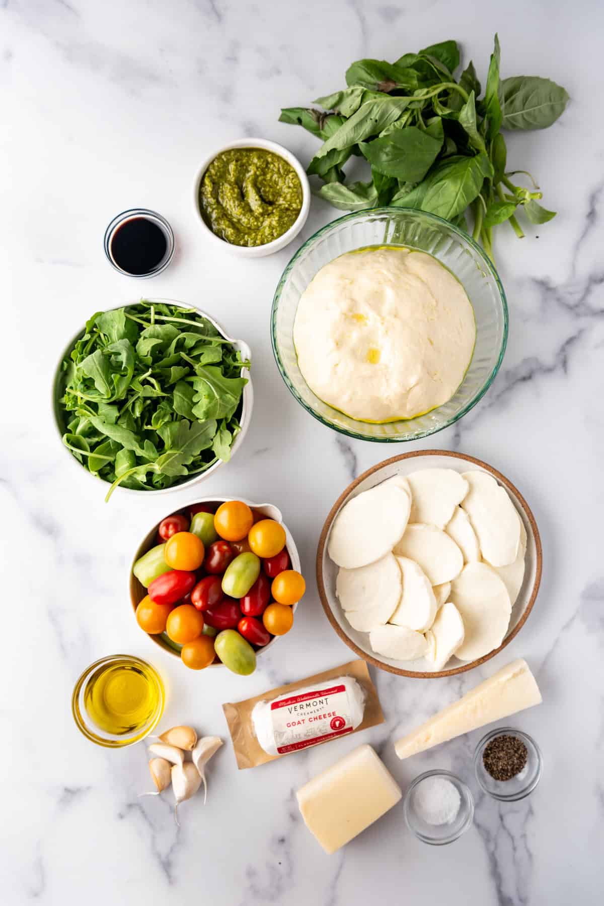 Ingredients for making a four cheese pizza with tomato and arugula topping.