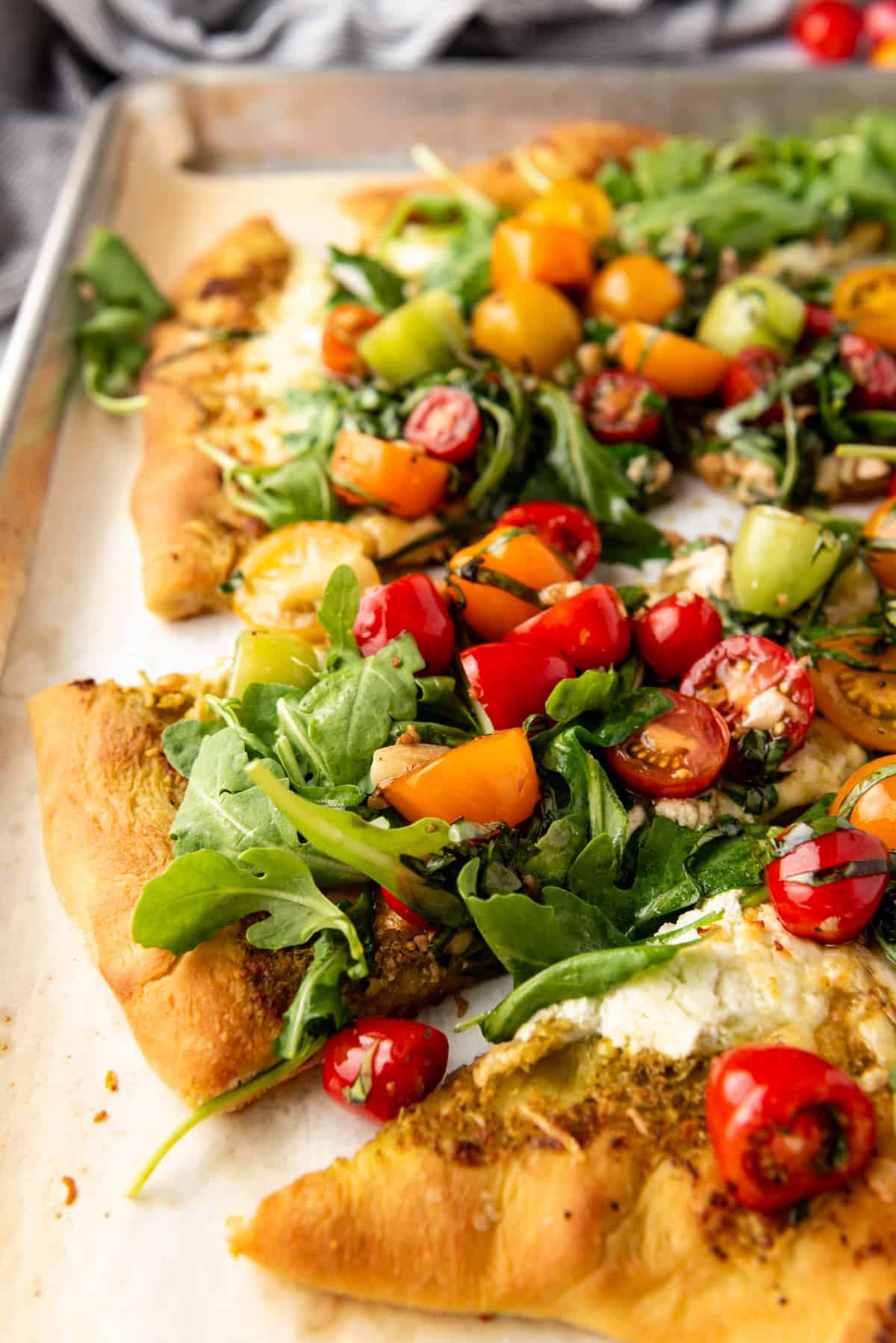 A side view of a four cheese pizza with tomato arugula topping.