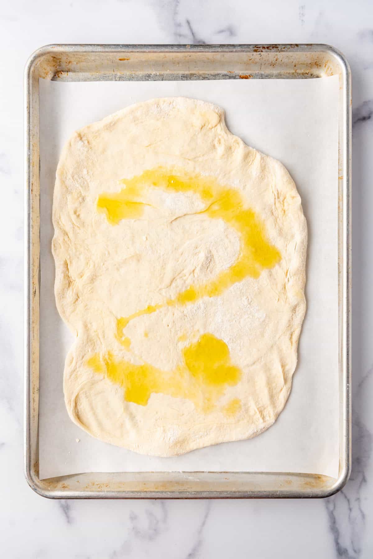 A drizzle of olive oil on pizza dough.