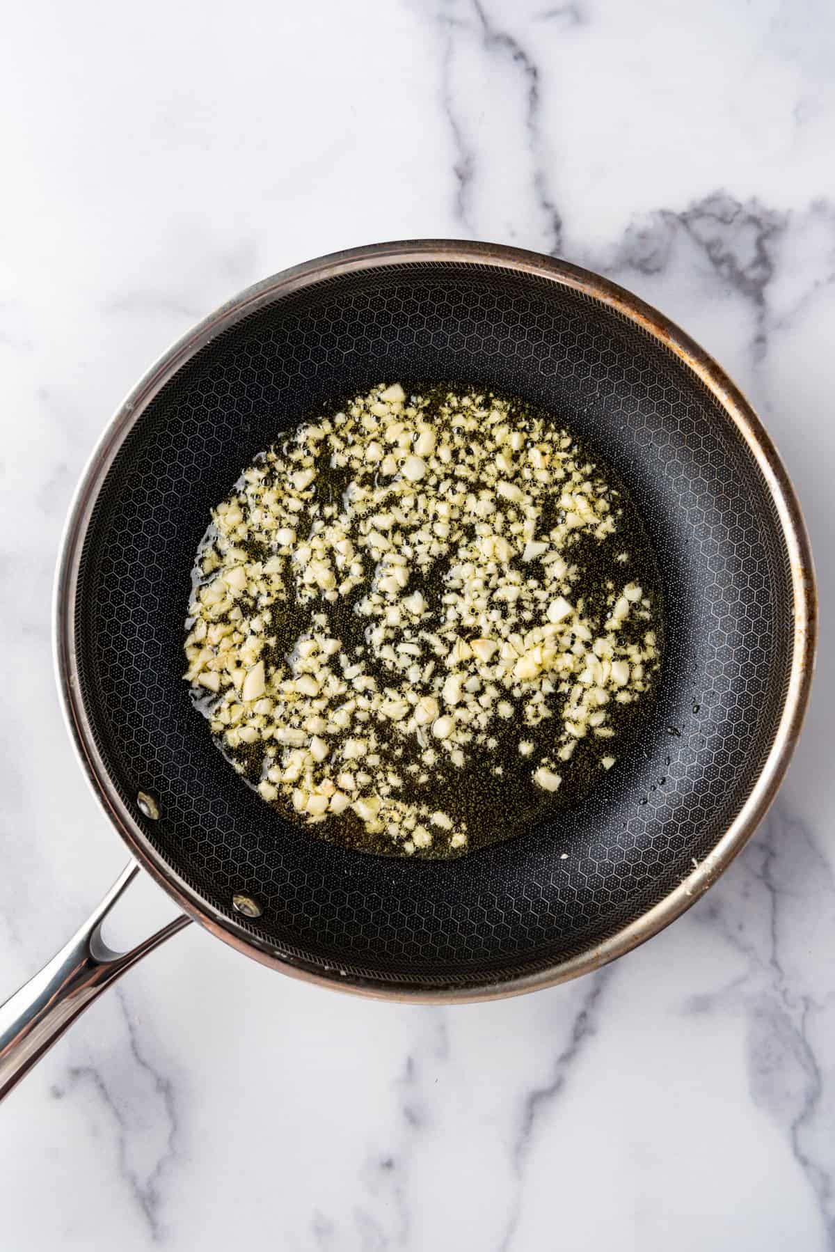 Cooking minced garlic in olive oil in a pan.