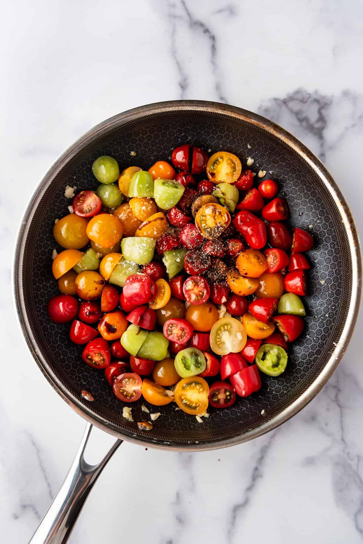 Adding salt and pepper to tomatoes and garlic in a pan.