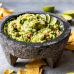A bowl of homemade guacamole surrounded by tortilla chips.