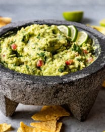 A bowl of homemade guacamole surrounded by tortilla chips.