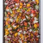 A baking sheet filled with roasted vegetables and sausages.