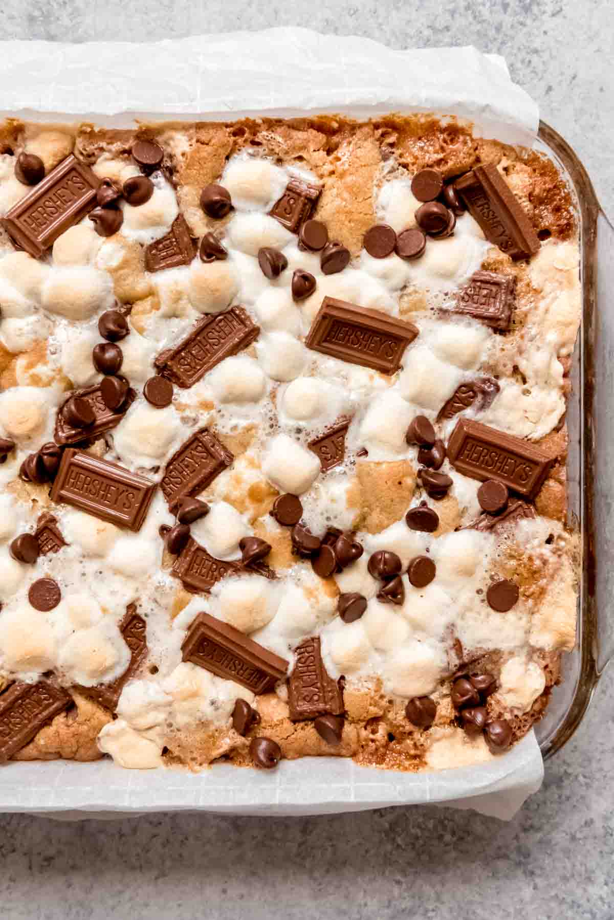 An image of s'mores cookie bars in a pan lined with parchment paper for easy removal.