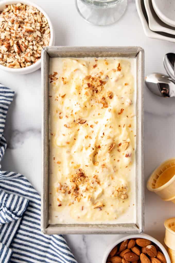 An overhead image of a batch of toasted almond ice cream in a loaf pan.