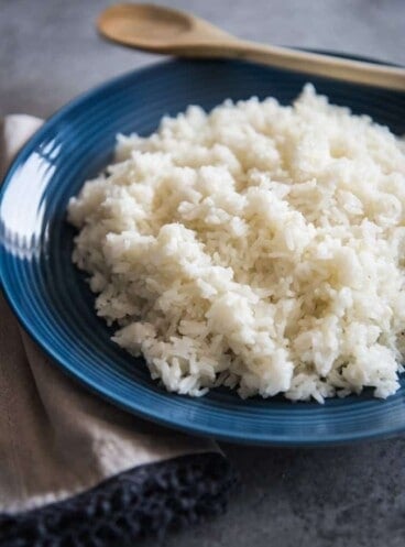 A blue plate with a pile of white rice on it.