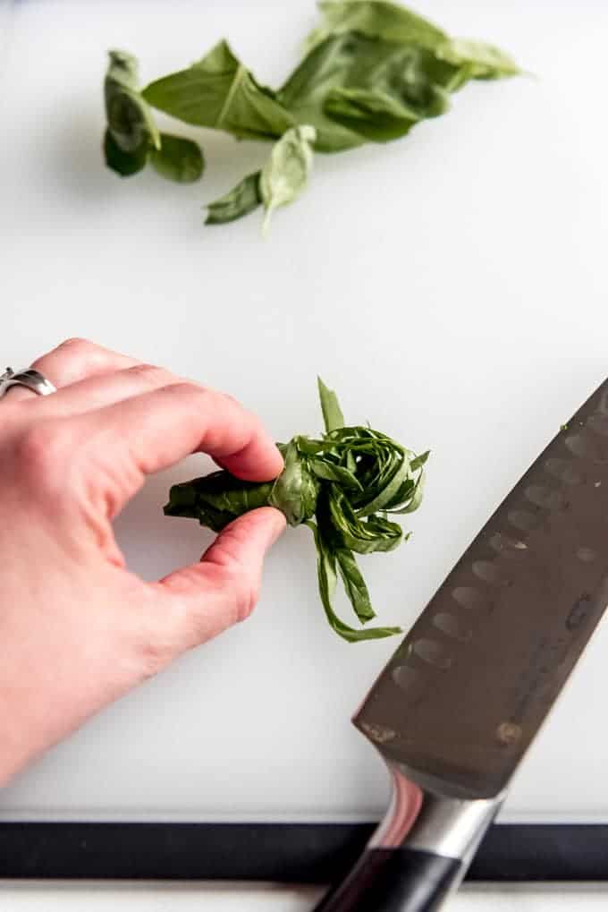 An image of basil being sliced into ribbons, a technique known as a chiffonade.