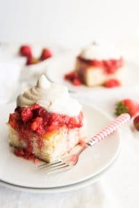 Slices of white cake topped with mashed strawberries and freshly whipped cream for strawberry shortcake.