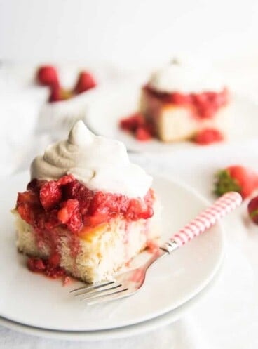 Slices of white cake topped with mashed strawberries and freshly whipped cream for strawberry shortcake.
