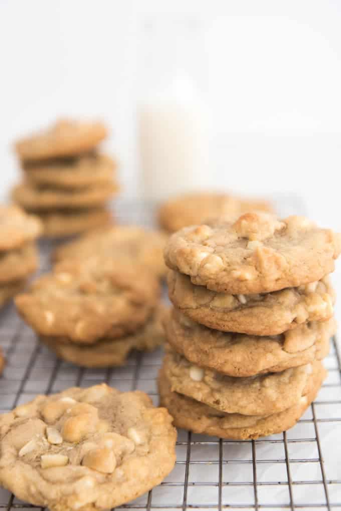 White chocolate macadamia nut cookies stacked into towers on a wire cooling rack.