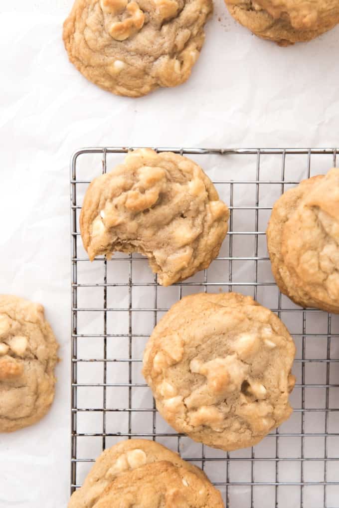 White chocolate macadamia nut cookies on a cooling rack with a bite taken out of one of them.