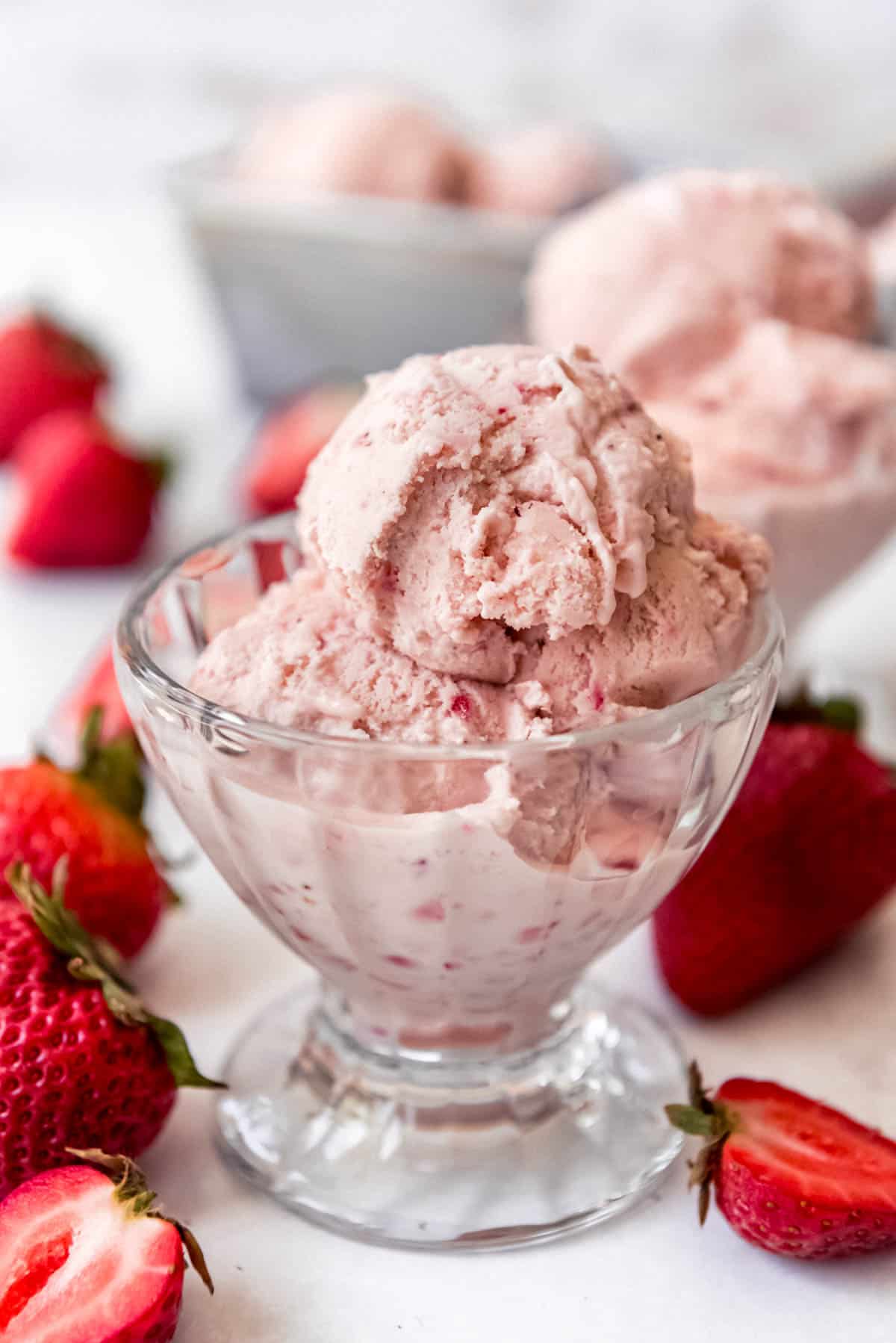 a small dish of strawberry ice cream surrounded by fresh strawberries