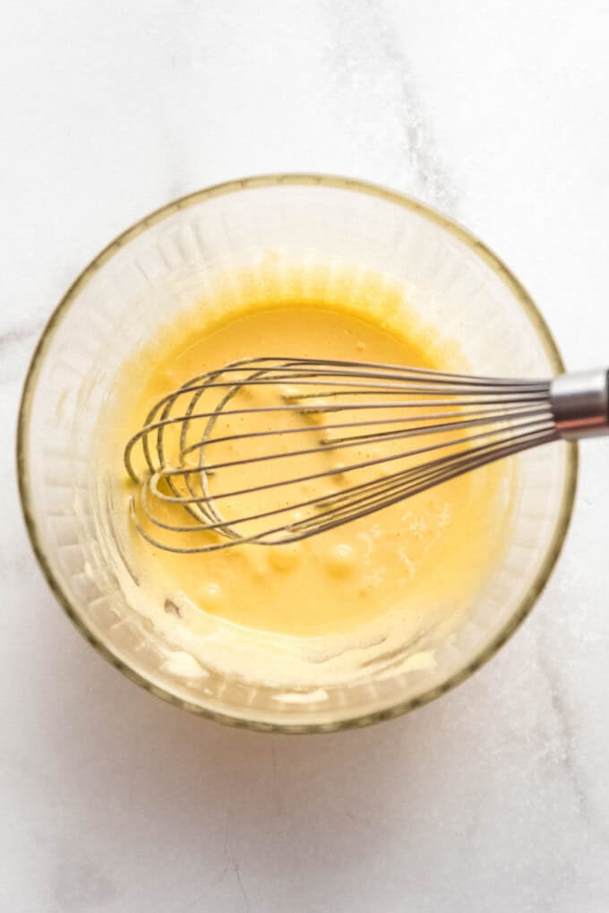 A whisk in a mixing bowl of eggs and sugar.