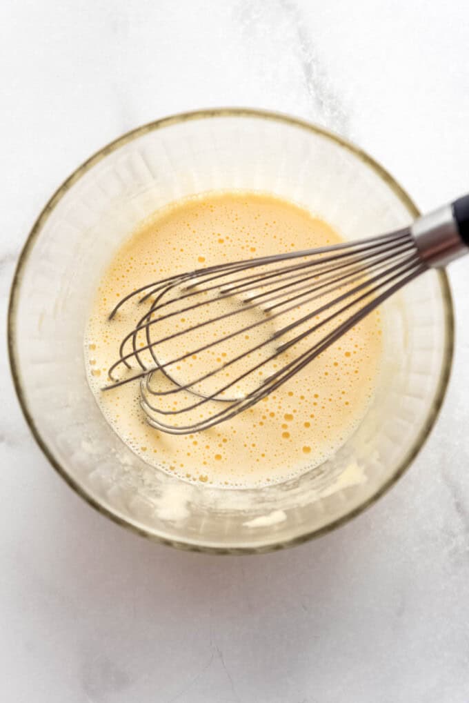 Whisked egg yolks and sugar in a bowl with a whisk.