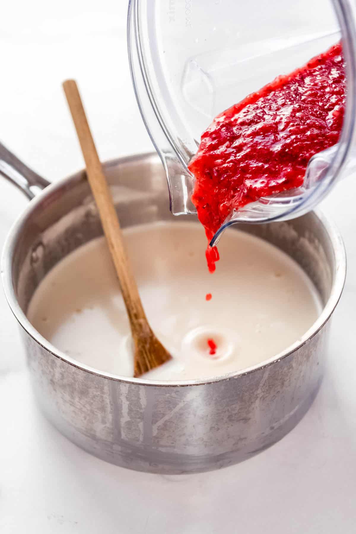 Strawberry puree being added to a custard ice cream base.