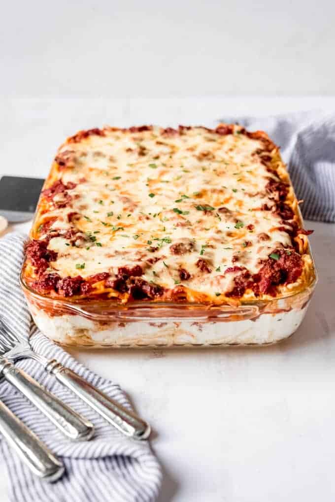 An image of a baked spaghetti casserole topped with melted mozzarella cheese and chopped parsley.