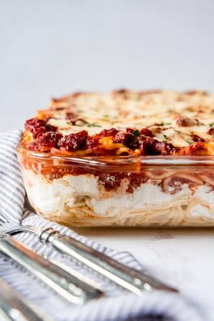 An image of a baked spaghetti casserole in a glass baking dish.