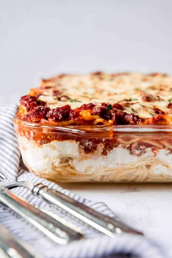 An image showing the layers of baked spaghetti pasta, sour cream and cottage cheese, and meat sauce baked into a casserole.