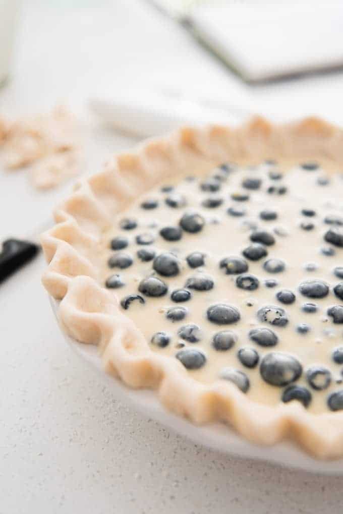 blueberries floating in custard in an unbaked pie shell