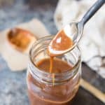 a spoon drizzling salted caramel back into a mason jar
